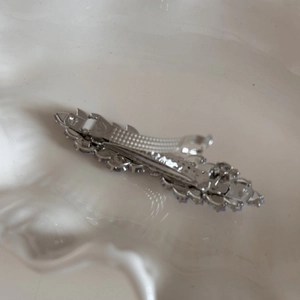 Detail of silver bow hair clip with sparkling rhinestones on an alligator base