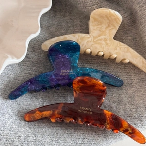 Detailed view of three large acetate hair claws in marble and tortoiseshell patterns