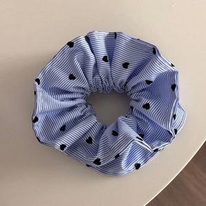 Vue détaillée d'un chouchou à rayures bleues avec des motifs de coeurs noirs et texture