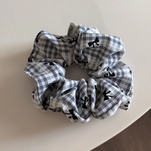 Détail d'un chouchou à carreaux avec motif nœud et étiquette tissée FMdrea sur fond blanc