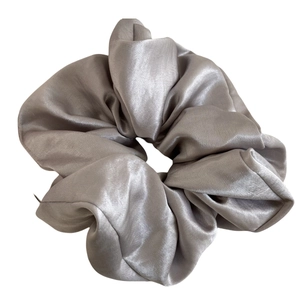 Glossy champagne satin scrunchie with elegant folds for a minimalist hair style