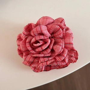 Macro detail of British style red and white plaid tweed rose fabric on a shark hair clip