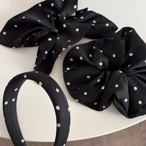 Detail view of black satin scrunchies and headband set with white floral prints