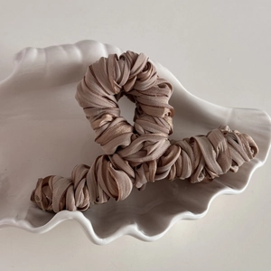 Close-up of elegant pleated champagne fabric wrapped hair claw clip on shell tray