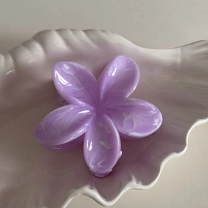 Macro shot of purple plumeria hair claw clip with marble texture on a shell-shaped plate