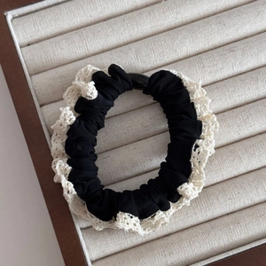 Close-up of black scrunchie with cream lace trim on a jewelry display tray