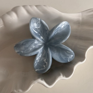 Macro detail of blue and white marble textured frangipani flower hair claw clip