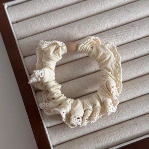 Close-up of beige lace scrunchie with soft fabric texture and elegant resin detail