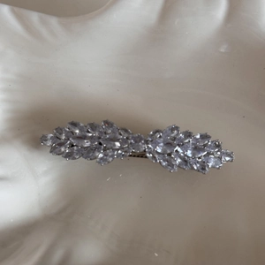 Close-up of a silver bow hair clip featuring sparkling marquise-cut rhinestones on ceramic