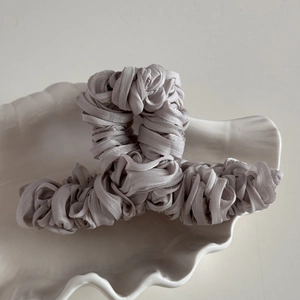 Detail view of silver-grey pleated fabric wrapped on a square hollow hair claw clip