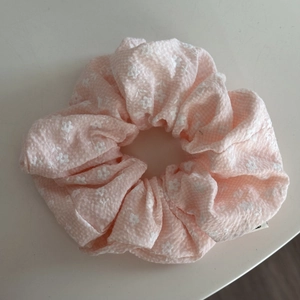 Detalle de coletero rosa claro con bordado de flores blancas y tela con textura