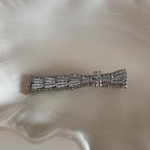 Detail of silver hair clip with layered round and trapezoidal rhinestones on white tray