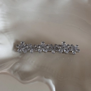 Detail of silver floral hair clip with marquise cut rhinestones on a white ceramic tray
