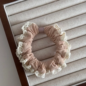 Detail of Korean style beige scrunchie with delicate lace edges on linen display