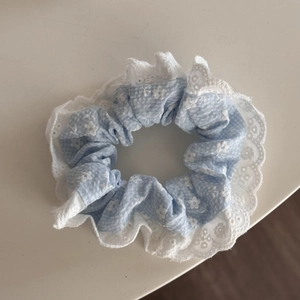 Detalle de coletero azul claro floral con bordes elegantes de encaje bordado blanco