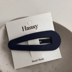 Close-up of a blue fabric teardrop hair clip on a white handmade display card