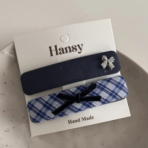 Close-up of blue solid and plaid fabric hair clips with bow details on a display card