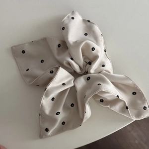 Detail view of cream floral satin hair scrunchie with elegant black flower pattern