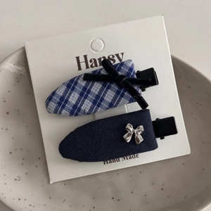Detailed view of blue plaid and navy fabric hair clips with bow knots on a ceramic tray