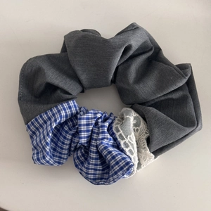 Close-up of blue-grey patchwork scrunchie featuring plaid fabric and white lace detail