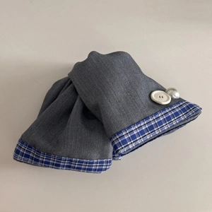 Detail of blue-grey plaid fabric cuff with white button and pearl bead decoration