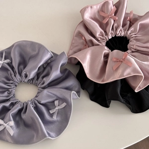 Detail of satin scrunchies in purple, pink and black with delicate bow embellishments