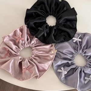 Three elegant satin scrunchies in black, pink, and grey with bow accents and gold charms