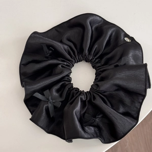 Detailed macro view of large black satin scrunchie with bows and silver brand tag
