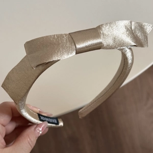 Vue détaillée du serre-tête en satin doré champagne avec un nœud fait à la main