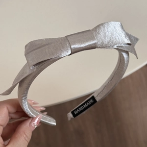 Détail d'un serre-tête en satin gris argenté avec étiquette textile faite à la main