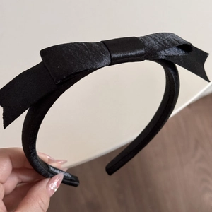 Vue détaillée de l'étiquette faite main sur un serre-tête en satin noir avec nœud élégant