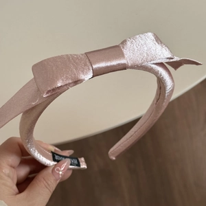 Détail du serre-tête en satin rose avec étiquette fait main et nœud double couche