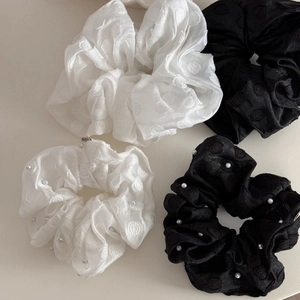 Detailed view of black and white scrunchies with elegant pearls and jacquard fabric texture