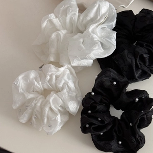 Detail of four jacquard scrunchies in black and white with elegant pearl bead accents