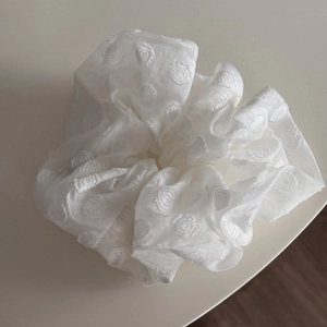 Detail of white organza scrunchie featuring elegant pearl embroidery and sheer fabric