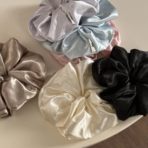 Macro detail of glossy satin fabric texture on colorful large oversized hair scrunchies
