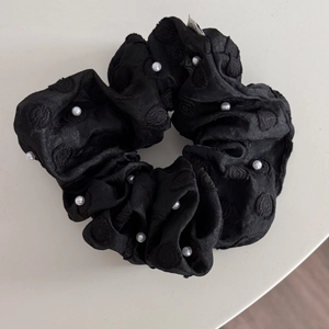 Detail of black satin scrunchie with white pearls and heart embroidery pattern