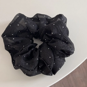 Gros plan d'un chouchou noir oversize avec strass brillants et texture en maille légère