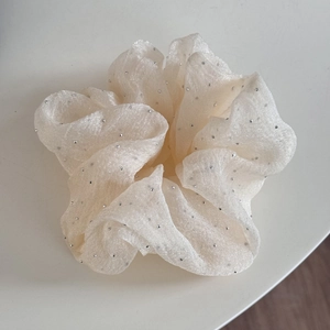 Détail d'un chouchou en tulle étoilé blanc avec strass brillants et plis doux multicouches