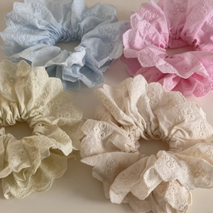 Détail de quatre chouchous en dentelle brodée aux couleurs pastel et bords festonnés
