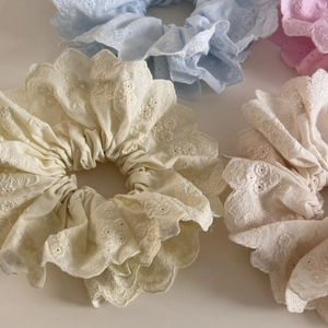 Détail de chouchous en dentelle aux tons pastels avec motifs de broderie florale ajourée