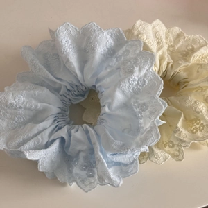 Détail de deux chouchous en dentelle de style français avec broderie florale bleue et blanche