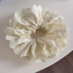 Vue détaillée du grand chouchou en dentelle blanche avec broderie à bord festonné