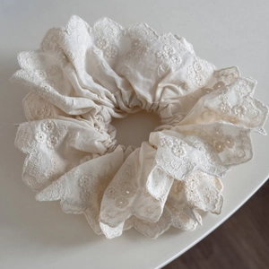Vue détaillée du chouchou en dentelle crème avec broderie florale complexe et bords festonnés