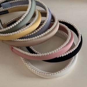 Detail of multi-color satin pearl headbands with handmade label on beige background