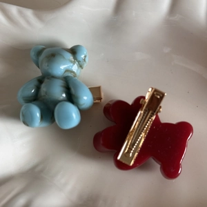 Detail of blue marble and wine red bear hair clips with golden metal duckbill clips