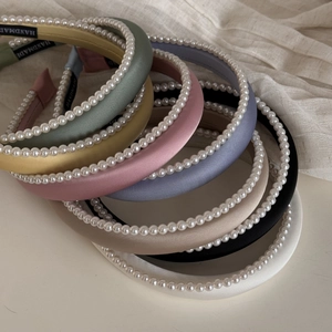 Detail showing various colors of padded pearl headbands with satin finish and handmade labels