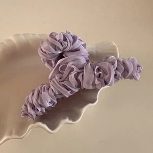 Detail of large purple pleated silk fabric hair claw clip on a white shell plate