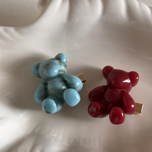 Detailed close-up of cute resin bear hair clips in light blue marble and ruby red