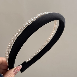 Detail of elegant black satin headband with double-layered white pearls for women
